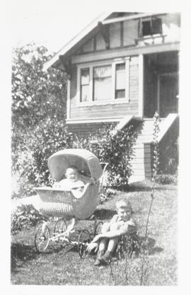 Muriel Bourne in wicker carriage with brother Howard Bourne in front yard of 852 Wollaston Street