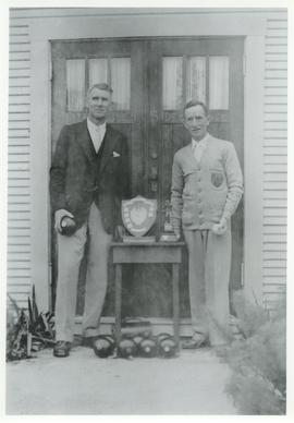 Mr. Stewart and unidentified man with lawn bowling trophies