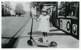 Millicent Hughes with her scooter in front of Hughes Confectionery store, Esquimalt Road