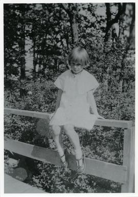 Millicent Hughes sitting on fence at 875 Esquimalt Road