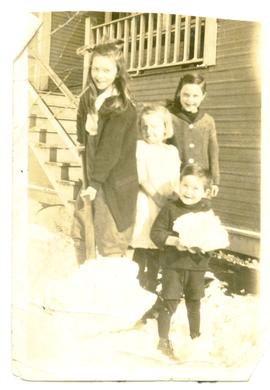 Four children on deck stairs playing with snow