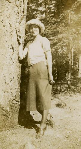 Woman leaning against fir tree