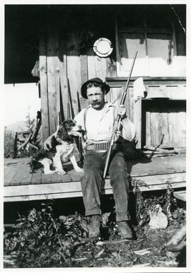 Tom Bowling Young, resident of Esquimalt, at his Sooke cabin with his dog and hunting rifle