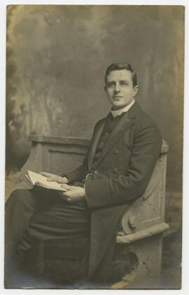 Studio portrait of a man seated with a book