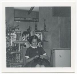 Young girl sitting by a Christmas Tree with dog on her lap