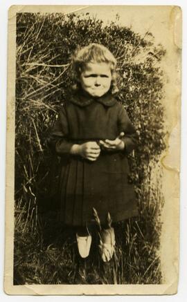 Girl wearing a coat standing in a garden